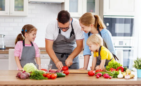 happy family with children preparing vegetable salad at hom
