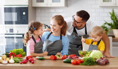 happy family with children preparing vegetable salad at hom clipart