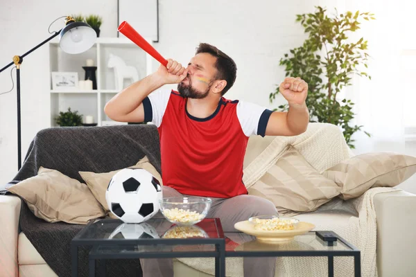 male soccer  fan watching a football match at home on T