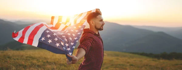 Natur で夕日を楽しむアメリカ合衆国の国旗を持つ若い幸せな男 — ストック写真