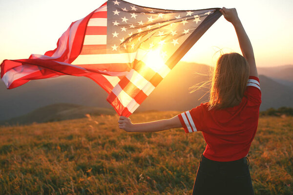 young happy woman with flag of united states enjoying the sunset on natur