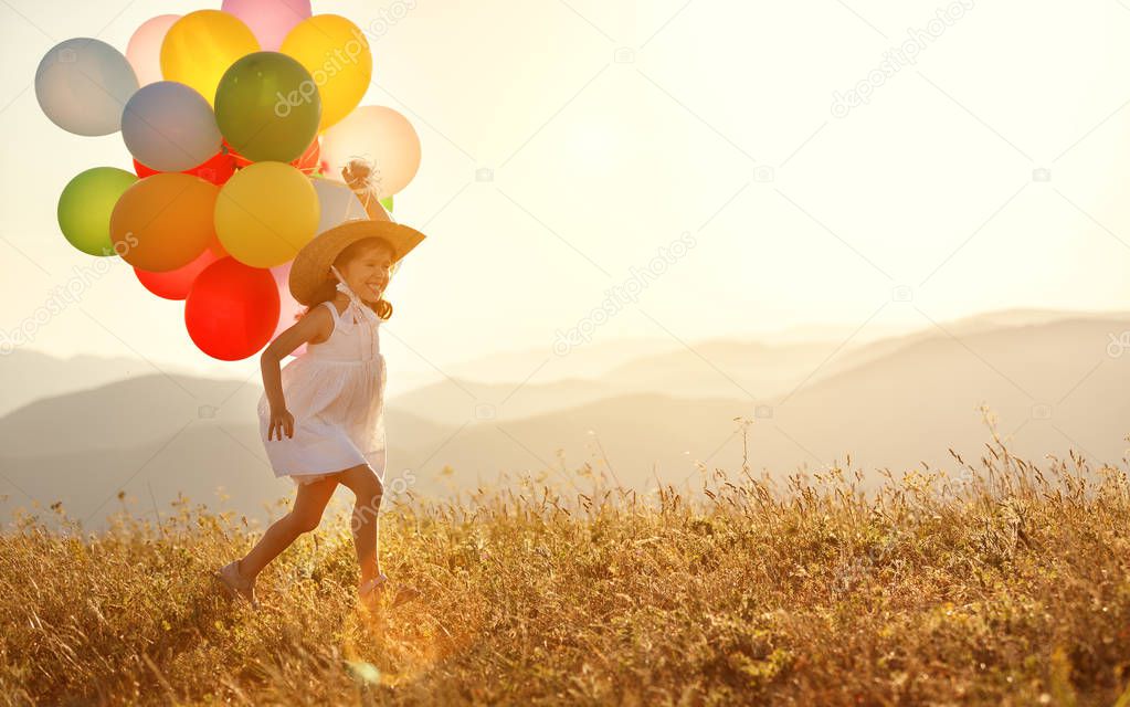 young happy child girl with balloons at sunset in summe