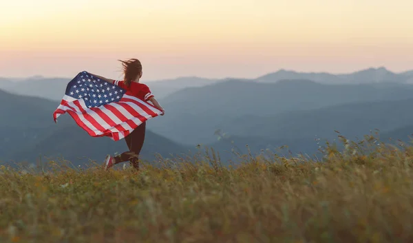 Natur で夕日を楽しむアメリカ合衆国の国旗を持つ若い幸せな女 — ストック写真