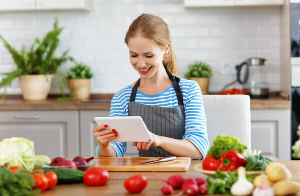 happy woman preparing vegetables in kitchen on prescription with a table
