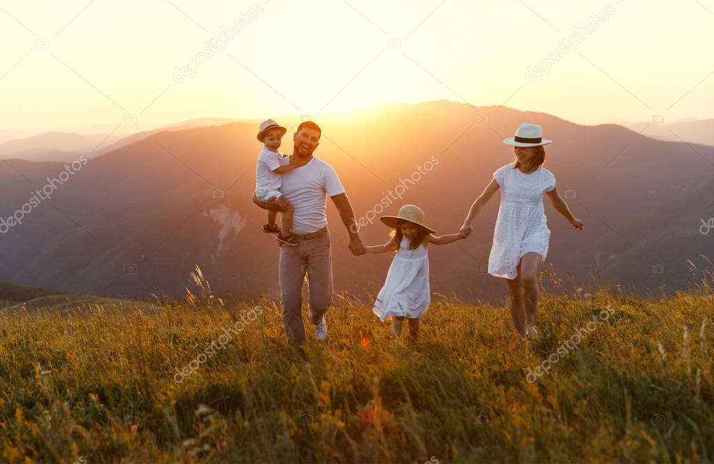 Happy family: mother, father, children son and  daughter on nature  on sunse