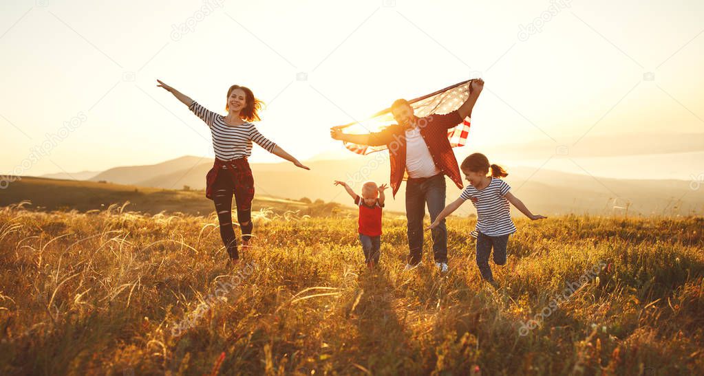 happy family with the flag of america USA at sunset outdoor