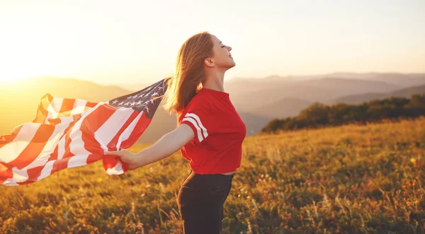 Natur で夕日を楽しむアメリカ合衆国の国旗を持つ若い幸せな女 — ストック写真