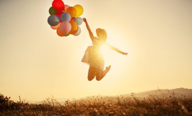 Balonlar summe batımında olan mutlu kadın