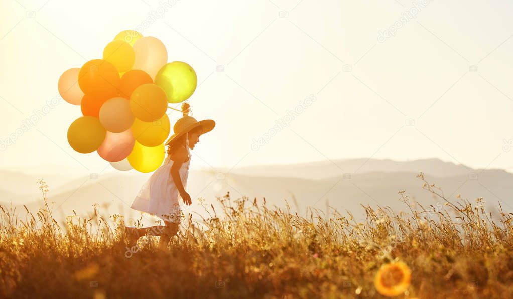 young happy child girl with balloons at sunset in summe