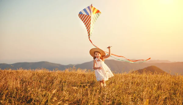Günbatımında açık bir uçurtma ile çalışan kız mutlu çocuk