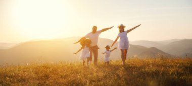 Mutlu aile: anne, baba, çocuklar gün batımında doğada oğul ve kız