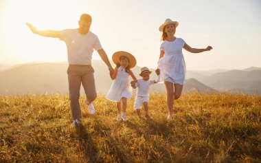 Mutlu aile: anne, baba, çocuklar gün batımında doğada oğul ve kız