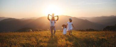 Mutlu aile: anne, baba, çocuklar gün batımında doğada oğul ve kız
