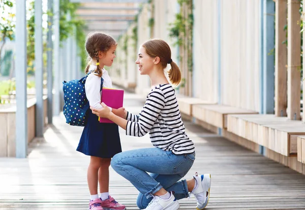 first day at school. mother leads a little child school girl in first grad