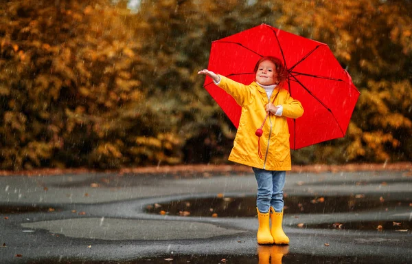 快乐的孩子女孩用伞和橡胶靴在秋天的沃尔玛的水坑里 — 图库照片