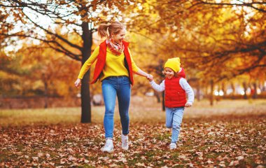 Mutlu aile annesi ve kızı sonbahar yürüyüşünde gülüp oynuyorlar.