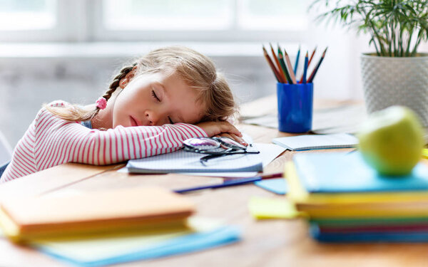 уставшая девочка заснула, когда делала домашнее задание, училась писать и читать в доме
