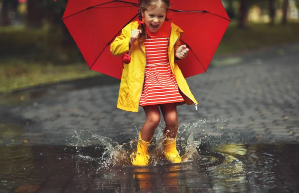 快乐的孩子女孩用伞和橡胶靴在秋天的沃尔玛的水坑里 — 图库照片