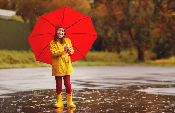 快乐的孩子女孩用雨伞和橡胶靴跳在水坑上的秋季沃尔玛 — 图库照片