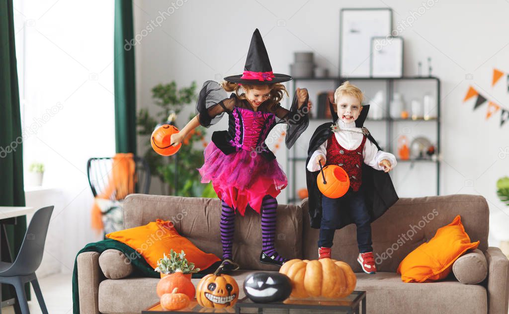 happy children in costumes of witch and vampire  preparing the home for holiday Hallowee