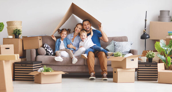 счастливая семья мать отец и дети переехать в новую квартиру и распаковать коробки