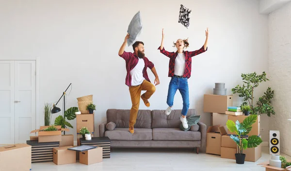 a happy young married couple moves to new apartment and laughing,  jump, fight pillow