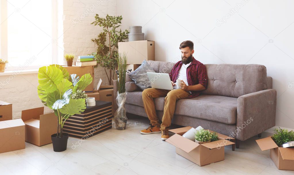 happy young man with boxes moves to new apartmen