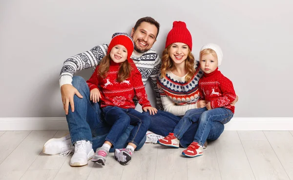 happy family mother, father and children in winter knitted hats and sweaters on gray backgroun