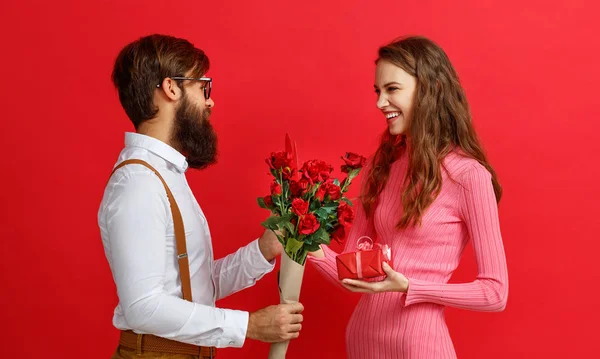 バレンタインデーのコンセプトです 幸せな若いカップルの心 赤の背景にギフト — ストック写真