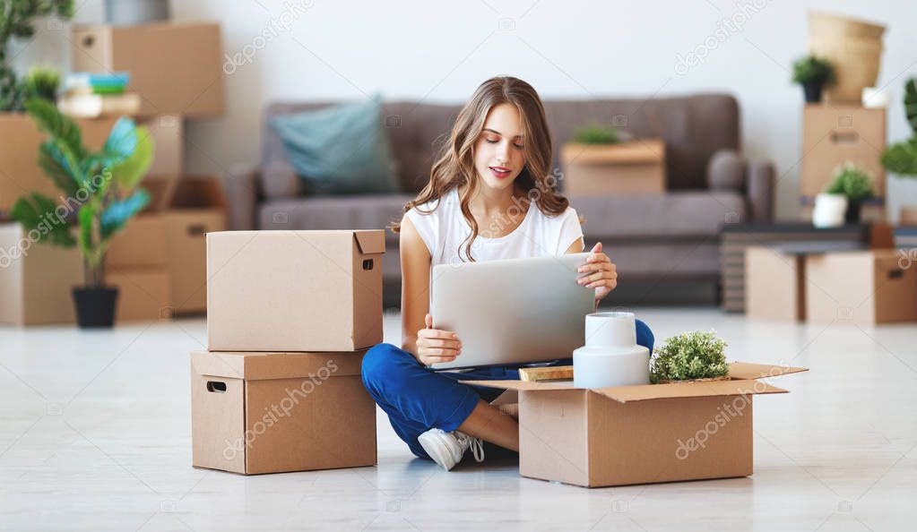 happy young girl with boxes moves to new apartmen