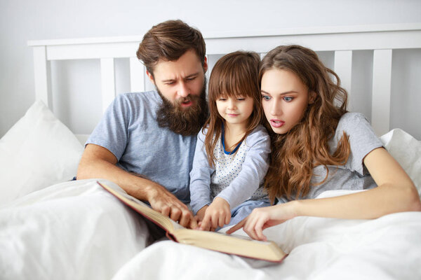 happy family mother, father and  father child daughter read a book, a fairy tale in be