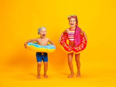 mutlu çocuk kız ve erkek yüzük çörek üzerinde renkli sarı adam yüzme ile mayo