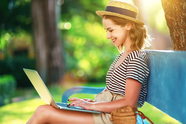 young woman working with a laptop on nature in summer in par