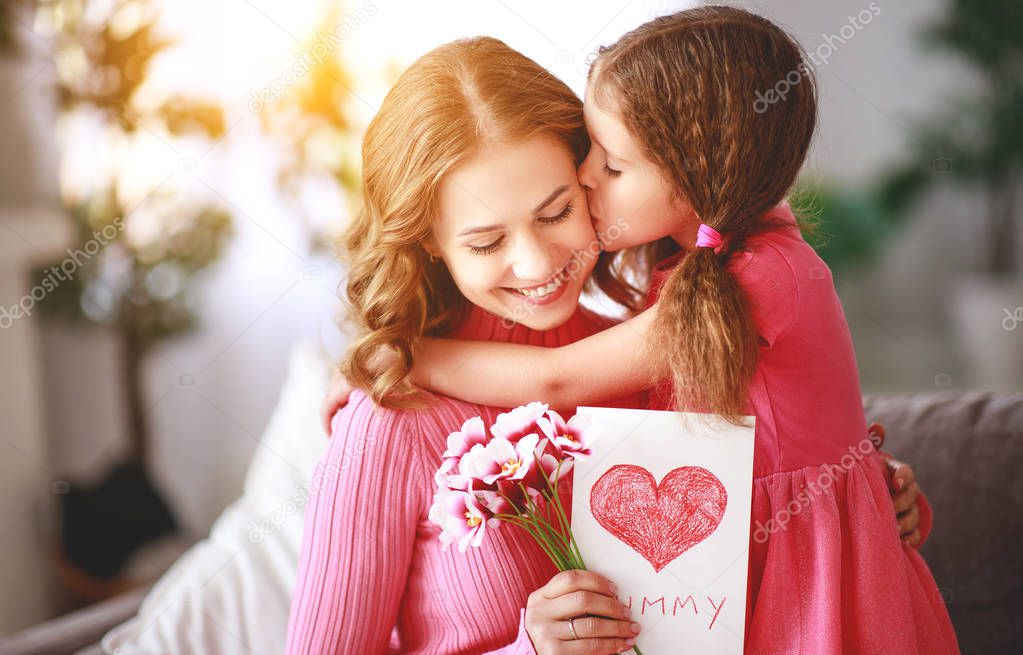 happy mother's day! child daughter congratulates mother and gives a bouquet of flowers and postcar