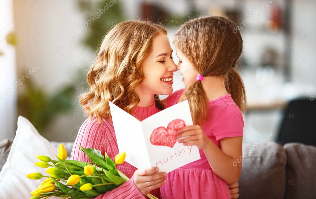happy mother's day! child daughter congratulates mother and gives a bouquet of flowers to tulips and postcar