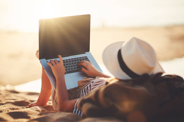 young woman working with a laptop on nature in summer beac
