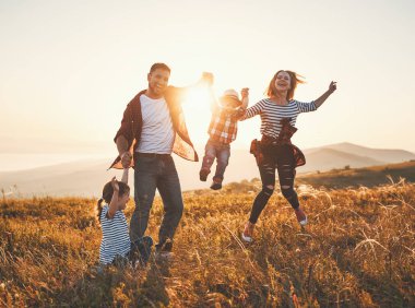 Mutlu aile: anne, baba, çocuklar gün batımında doğada oğul ve kız