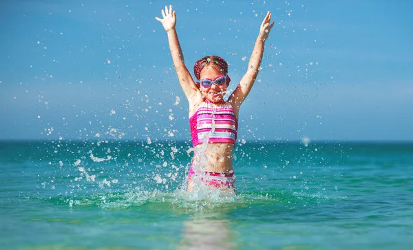 Счастливая девочка в купальнике и шляпе плавает в море на солнце — стоковое фото