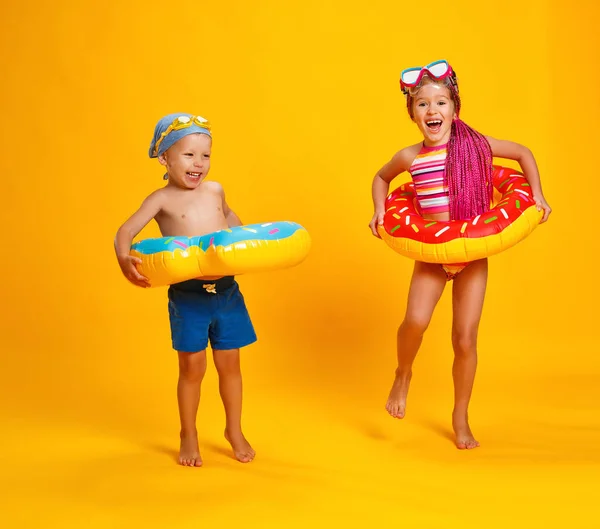 Niña y niño feliz en traje de baño con anillo de natación donut — Foto de Stock