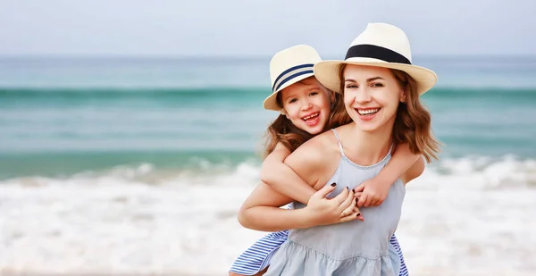 Famille heureuse à la plage. mère et enfant fille câlin au coucher du soleil — Photo