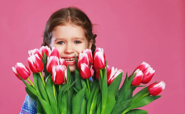 Niña divertida con ramo de flores en backgro de color rosa —  Fotos de Stock