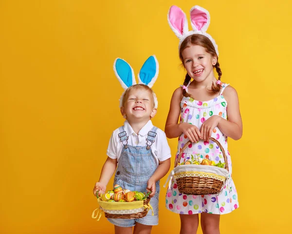 Divertido niño feliz con huevos de Pascua y orejas de conejo en yello — Foto de Stock