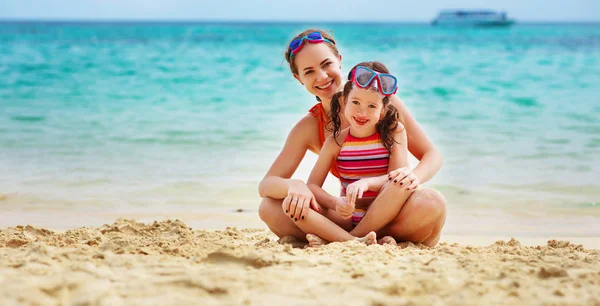 Feliz familia madre y chid hija en máscaras en playa en summe — Foto de Stock