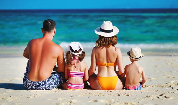 Feliz familia padre, madre e hijos espalda en la playa en sí — Foto de Stock