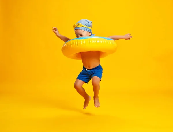 Glücklicher Junge im Badeanzug mit Schwimmring-Donut auf farbigem — Stockfoto