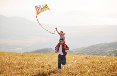 mutlu aile baba ve çocuk kız uçurtma çayır üzerinde denize indirmek