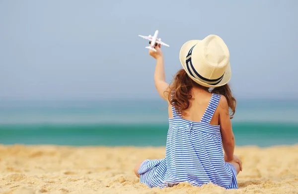 Child girl with toy model airplane on the sea on the beach — Stock Photo, Image