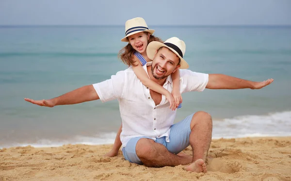O familie fericită pe plajă. tată și fiică copil îmbrățișare pe mare — Fotografie, imagine de stoc