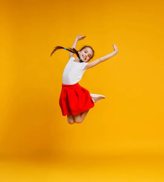 Engraçado criança menina saltando em colorido amarelo backgroun — Fotografia de Stock