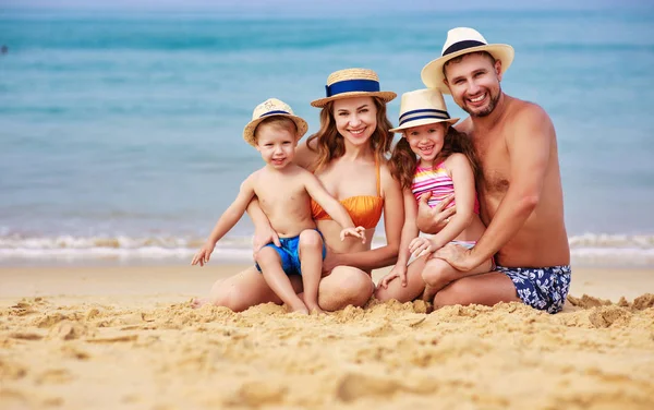 Feliz familia padre, madre e hijos en la playa en sí — Foto de Stock